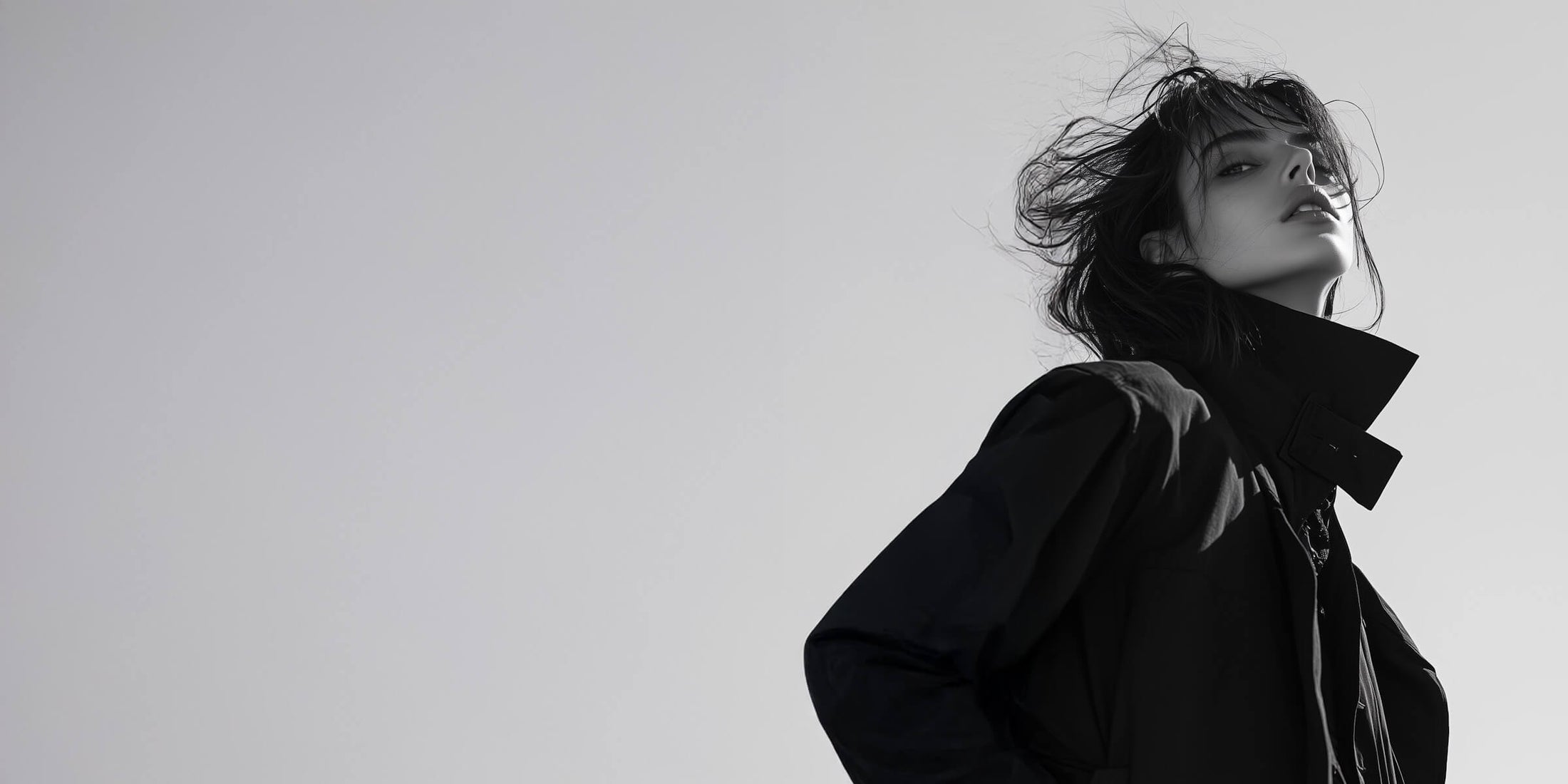 Woman wears a dark parka, black hair blowing in the wind.