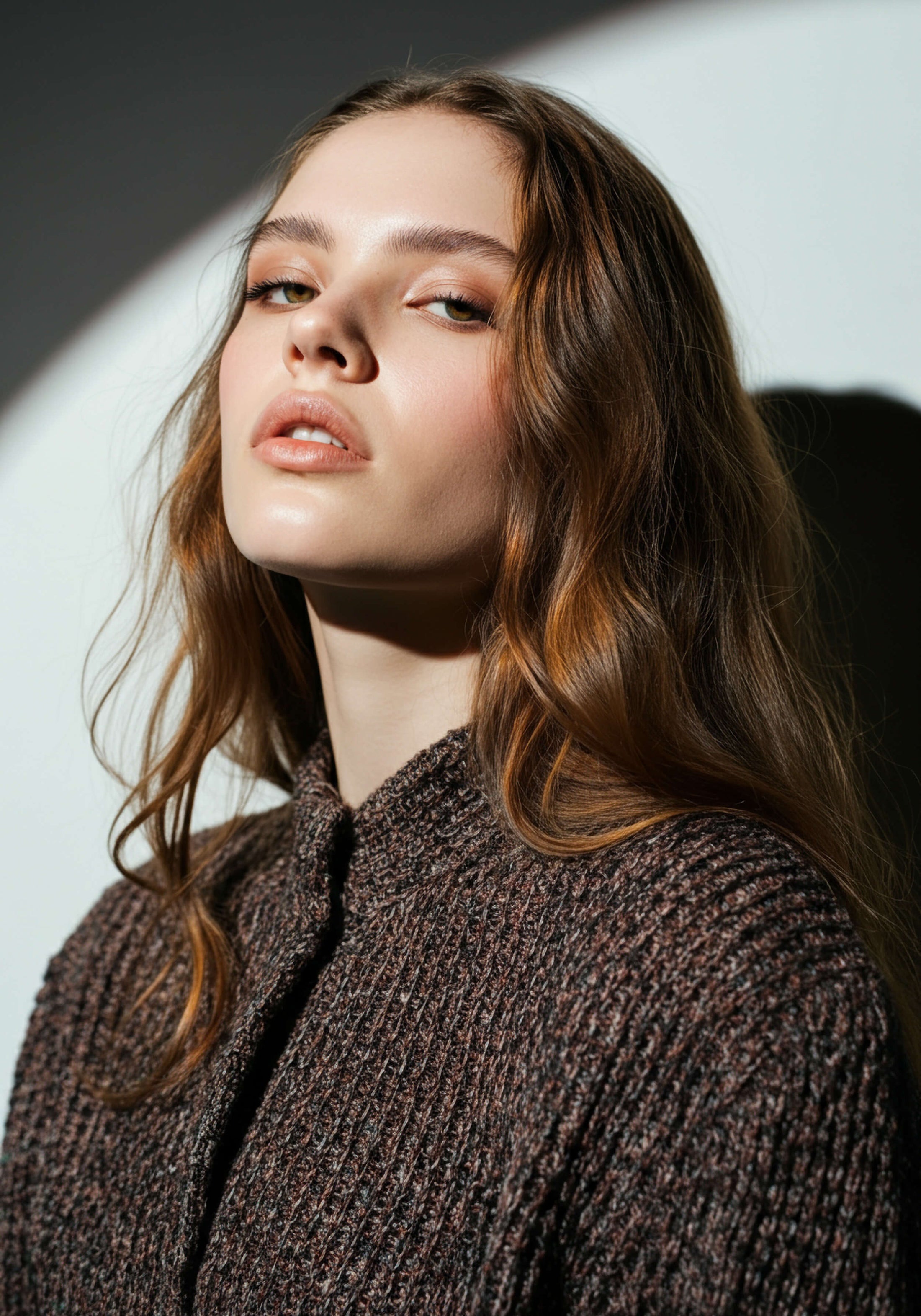 Model with long red hair wears brown knit and looks at the camera with attitude.